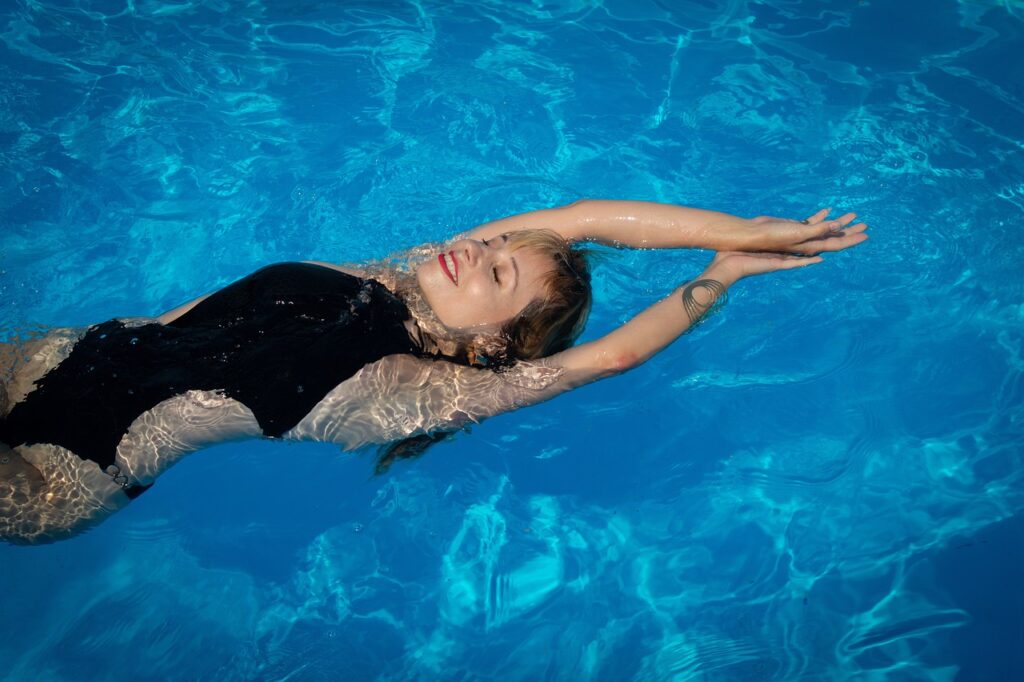 girl floating on back in swimming pool